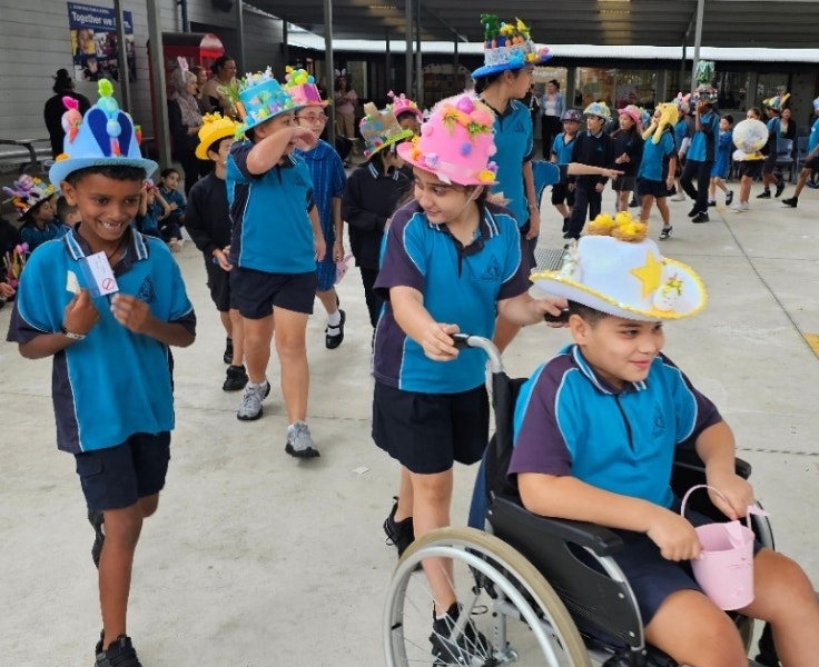 A parade of students in handmade easter hats walking around the school
